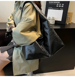 Close-up of a black oversized faux leather hobo tote bag with a glossy wax-like texture