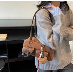 Détail du sac polochon en daim marron avec deux poches et charm ours en peluche