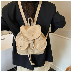 Retro khaki drawstring backpack with leather buckle straps worn over a black blazer