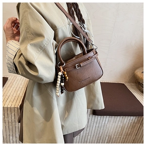 Detailed side view of brown square shoulder bag with colorful bead tassel and metal buckle