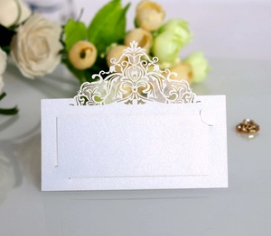 Close-up of laser-cut wedding place card with elegant crown lace pattern on pearl paper