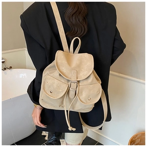 Detail of vintage beige backpack with buckle straps worn over a black blazer