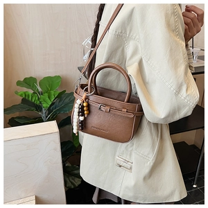Brown vintage faux leather square bag with bead charm shown on a stylish trench coat model