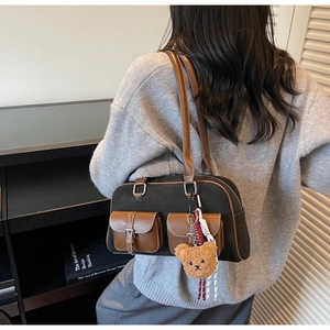 Détail du sac à bandoulière gris avec lanières brunes et breloque ours sur modèle