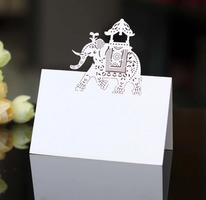 Detailed laser-cut elephant place card in white paper on reflective black surface