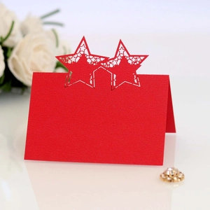 Detail of red laser-cut star place card on white floral background for weddings