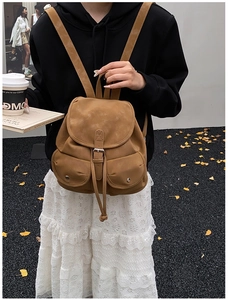 Vintage brown leather backpack featuring drawstring flap closure and dual front snap pockets