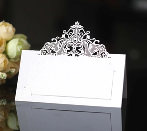 Detail of laser-cut lace pattern on white wedding table place card for event seating