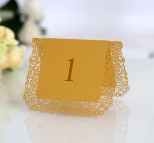Close-up of golden laser-cut table number one with elegant lace hollow floral details