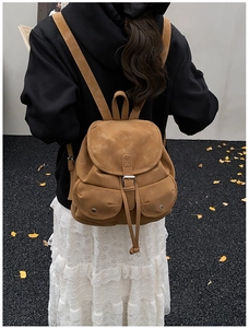 Detailed view of camel faux-suede backpack with vintage buckles and drawstring pockets