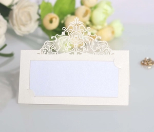 Detail of laser cut white lace place card with pearlescent finish and crown motif