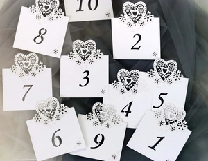 Detailed laser-cut heart and floral design on white wedding table number cards 1-10