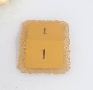 Close-up of laser-cut gold lace table number card with floral hollowed-out patterns