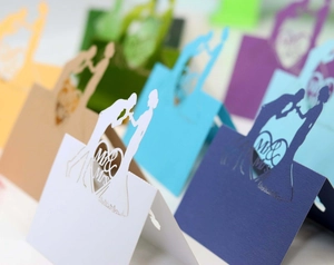 Detail of laser-cut heart Mr & Mrs wedding place cards in various elegant paper colors