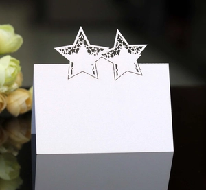 Laser cut white star table card with hollow patterns on reflective dark surface