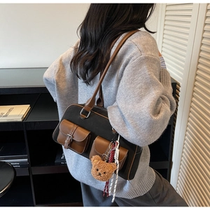 Détail du sac Boston en toile avec poches en cuir, bandoulière et breloque ourson