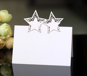 Detail of laser-cut star design on white wedding place cards with hollow star pattern