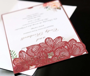 Close-up of laser-cut burgundy floral invitation pocket with printed wedding insert card