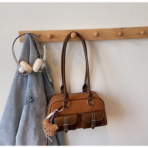 Détail du sac Boston en daim marron avec poches à rabat et porte-clés ours en peluche