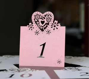 Macro detail of laser-cut floral heart wedding table number card in pink pearlescent paper