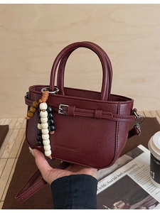 Chic burgundy square crossbody bag with wooden bead charm on a wooden background