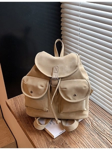 Retro cream large-capacity travel backpack with flap closure on a rustic wooden bench