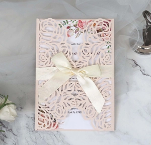 Detail of laser-cut rose floral wedding invitation with cream satin bow and floral inner card