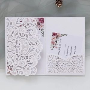Detail of laser-cut white wedding invitation with floral insert and RSVP card set