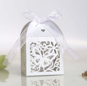 Macro shot of white laser-cut butterfly wedding candy box with elegant organza ribbon bow