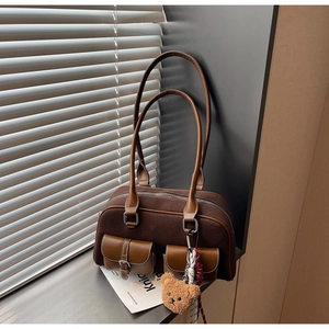 Détail d'un sac à bandoulière marron vintage avec un ours en peluche et deux poches avant