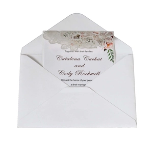 Detail of laser-cut lace wedding invitation with floral print and white envelope