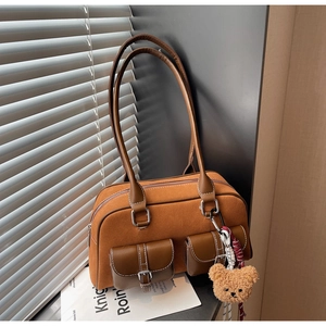 Détail du sac Boston en daim marron avec surpiqûres blanches et charme d'ours