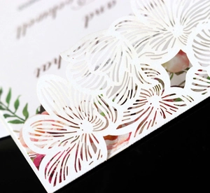 Macro shot of delicate laser-cut floral pattern on high-quality white pearl paper card