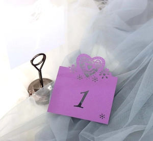 Detail of purple laser-cut wedding table number card with heart lace and metal stand