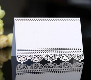 Macro shot of white laser-cut lace place card with pearlescent finish on black mirror