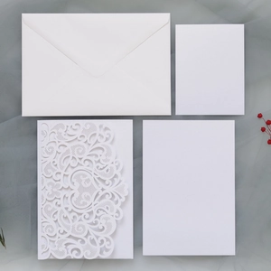 Laser-cut floral pattern invitations with white envelopes and cards on grey fabric
