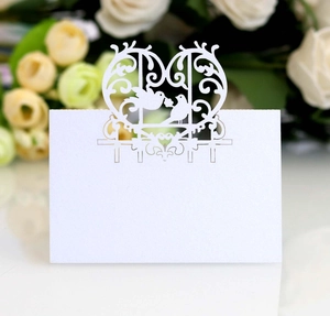 Laser cut white pearl paper wedding place card with lovebirds design on floral background