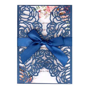 Detailed laser-cut rose patterns on dark blue wedding invitation with silk bow