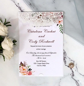 Detail of laser-cut lace wedding invitation with floral design on marble surface