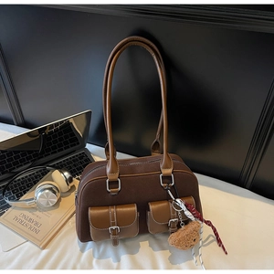 Détail du sac Boston en daim marron foncé avec deux poches et breloque en peluche