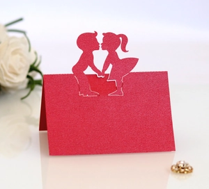 Laser-cut wedding place cards featuring a romantic couple design in red glitter paper