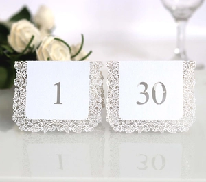 Detail of white laser-cut wedding table numbers with elegant rose lace patterns