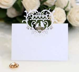 Detailed laser cut heart and kissing birds on a white wedding place card for guest seating