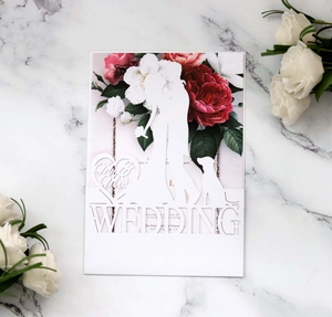 Macro detail of laser-cut white wedding invitation with Mr & Mrs silhouette and floral insert