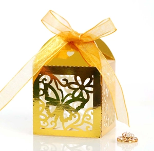 Laser-cut wedding favor box with butterfly pattern and gold ribbon on white background
