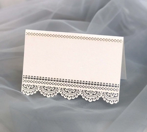 Close-up of white laser-cut lace wedding place card on blue tulle background