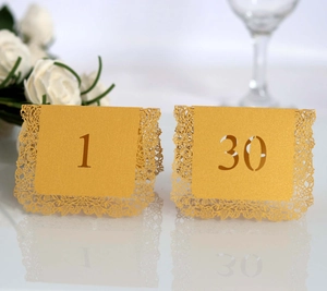 Detailed laser-cut gold table number cards with elegant rose floral patterns for weddings