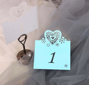 Detail of laser-cut heart place card showing intricate floral hollow design for weddings
