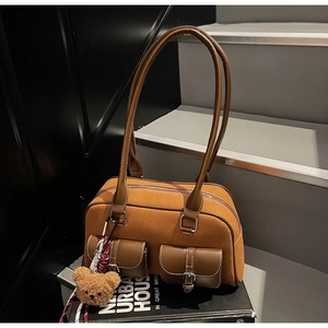Détail du sac bandoulière en daim avec poches à boucles et pendentif ours peluche