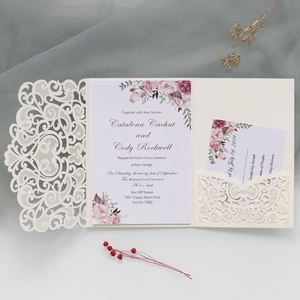 Detail of laser-cut wedding invitation set with floral card and elegant white lace cover